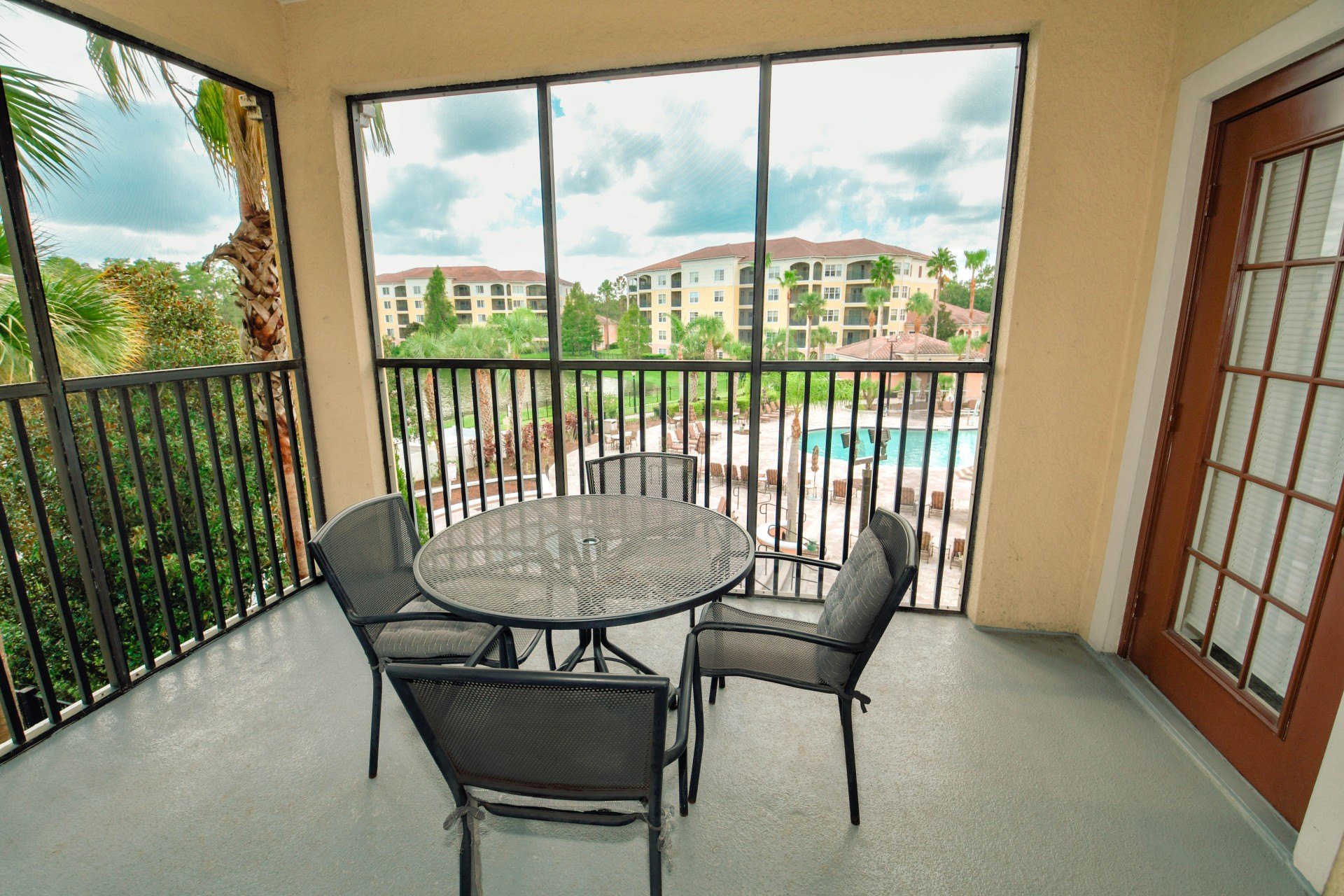 Private screened balcony with a table and chairs overlooking the resort